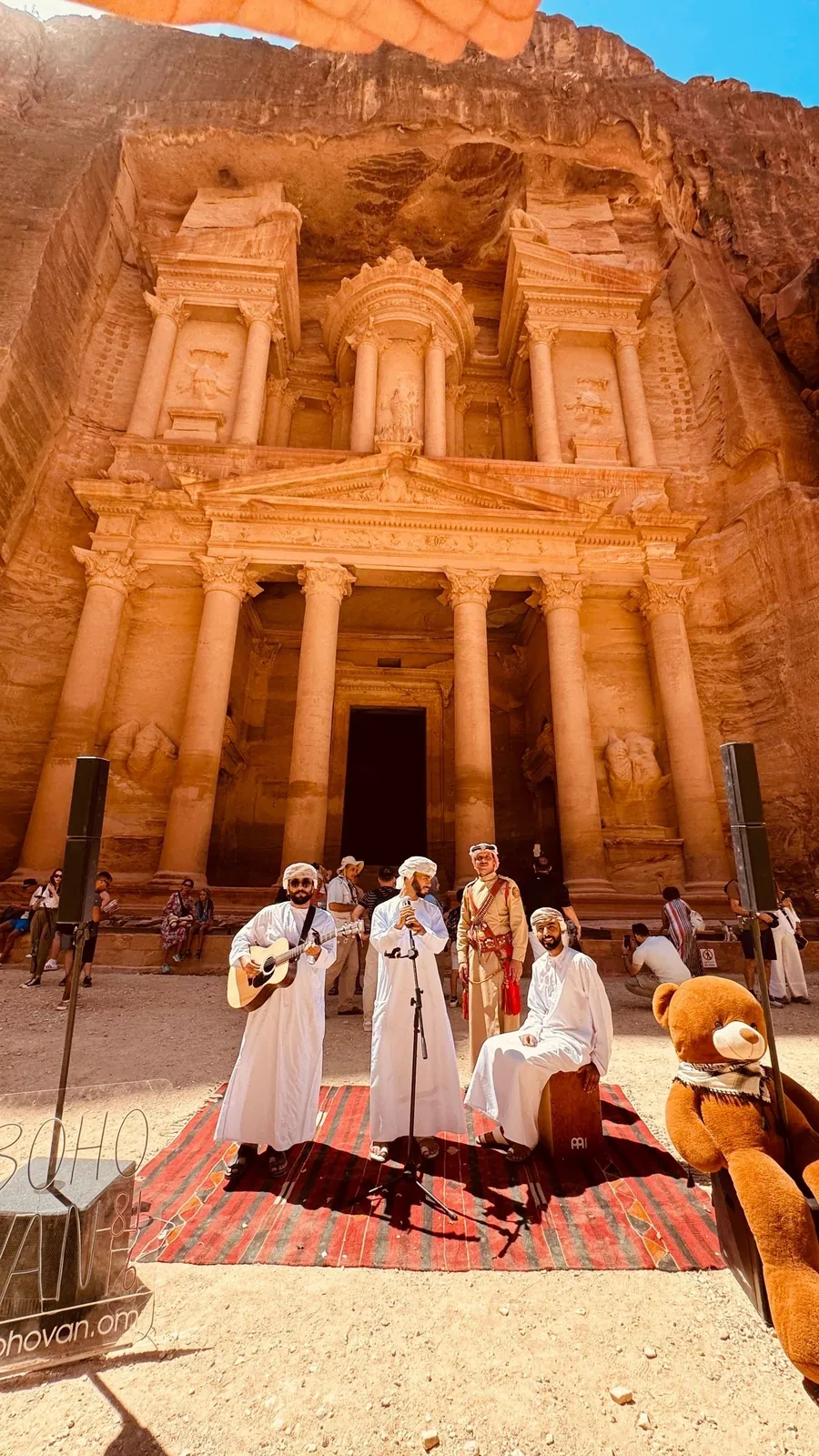Musicians in Omani dishdasha singing together in front of the Treasury at Petra