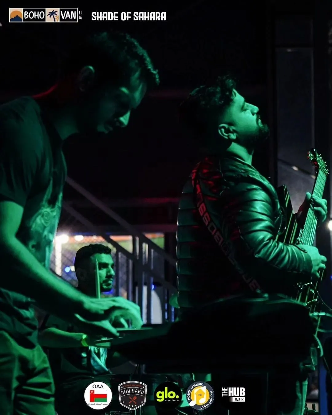 Two musicians performing in green stage light at Shade of Sahara